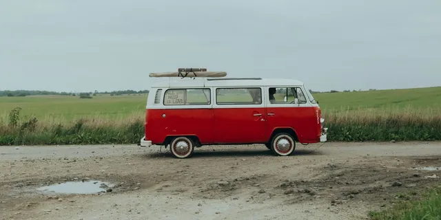Ein VW Bulli steht vor einem Grasfeld.