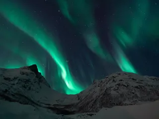 Night view of a snow-covered mountain and northern lights in the sky
