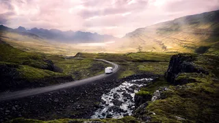 Camping Island: A campervan on a road in green mountain landscape on Iceland