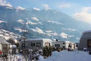 The campsite Natural Hell in winter. You can see the mountains in the background and some campers in the square.
