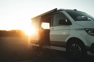 Frau bindet sich beim Ueberwintern in Portugal die Schuhe im Camper